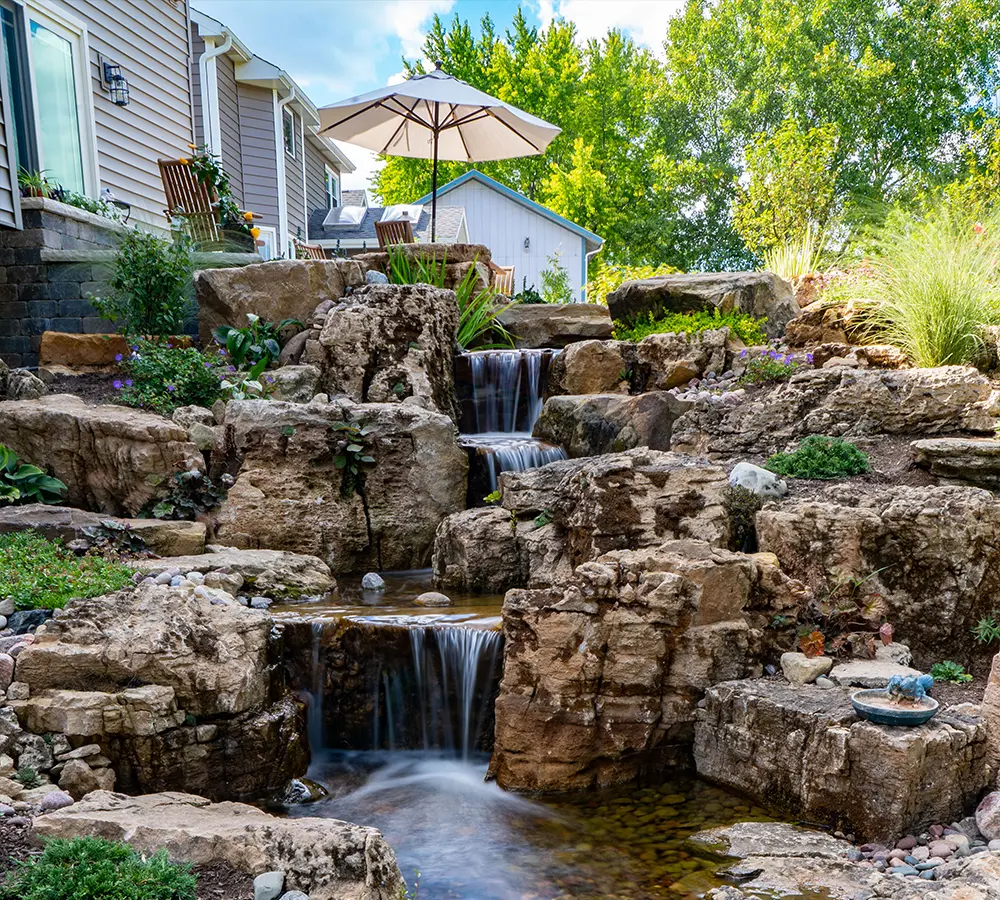 Pondless waterfall with cascading water over natural rock formations, creating a tranquil backyard feature.