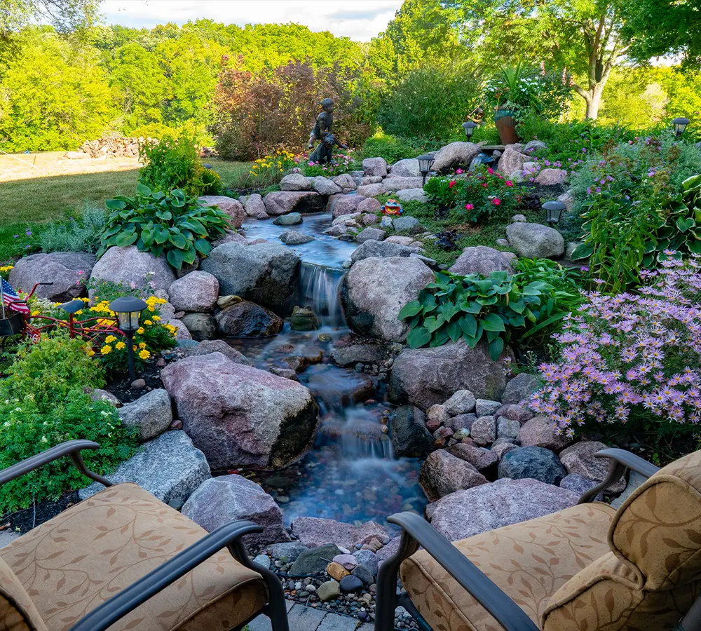 Beautiful backyard garden with cascading water feature and lush greenery.