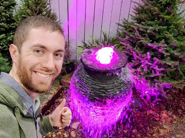 owner next to an illuminated garden fountain for custom water feature planning